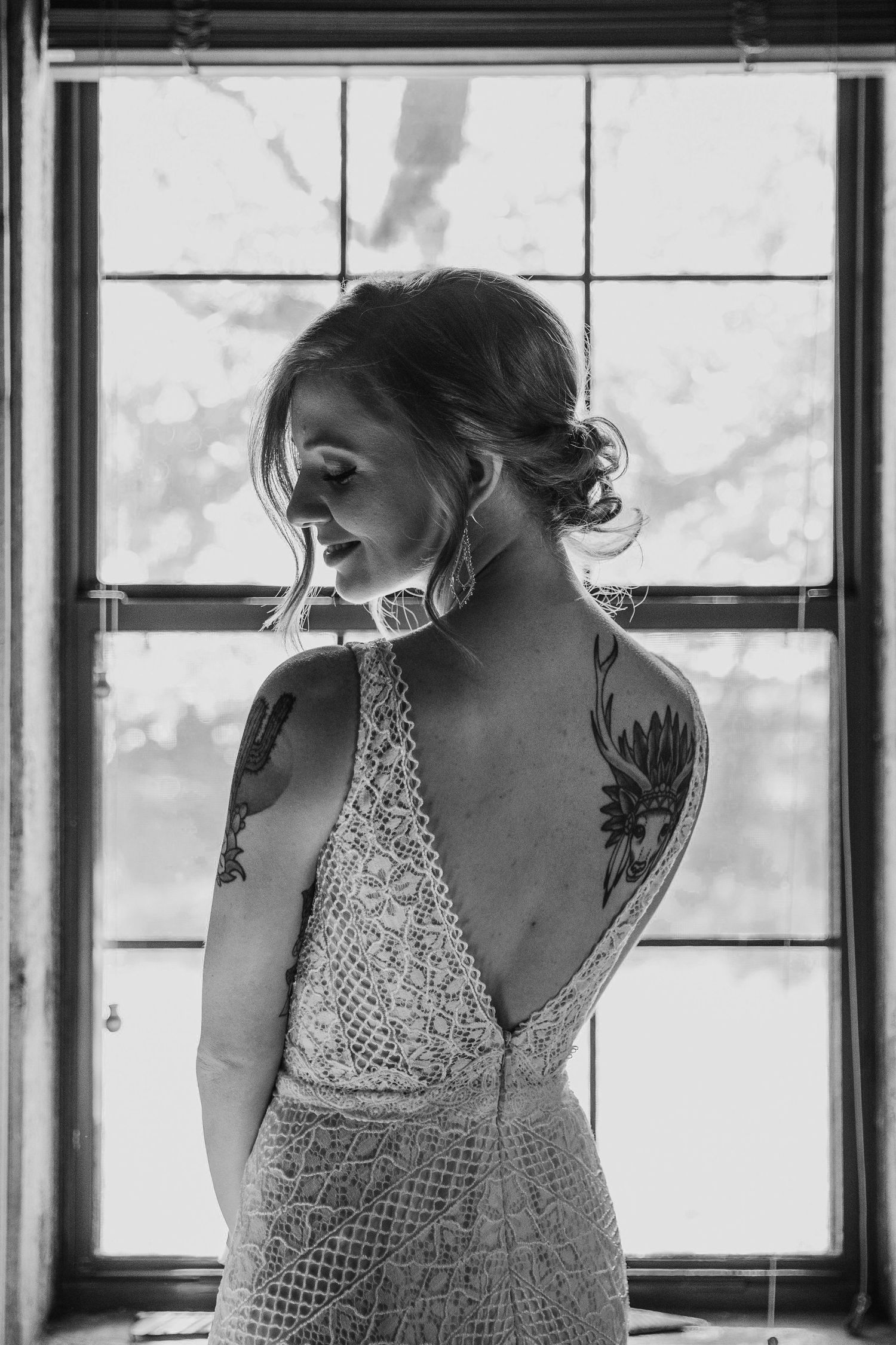 Black and white artistic portrait series of someone in a lace dress standing by a window in natural light.