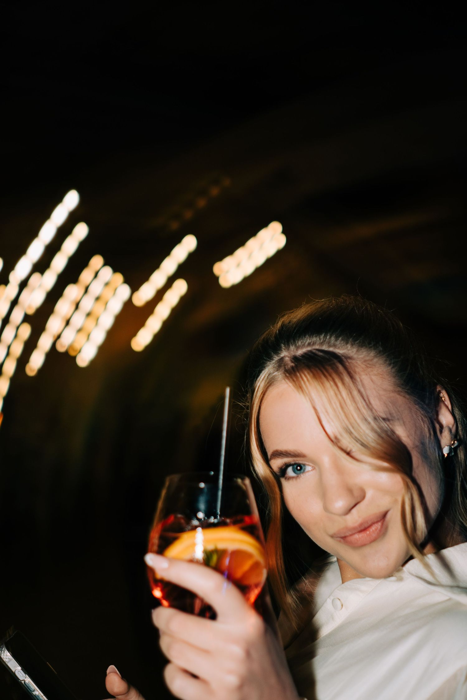 Artistic nighttime shots of someone holding a glowing drink at a celebration.