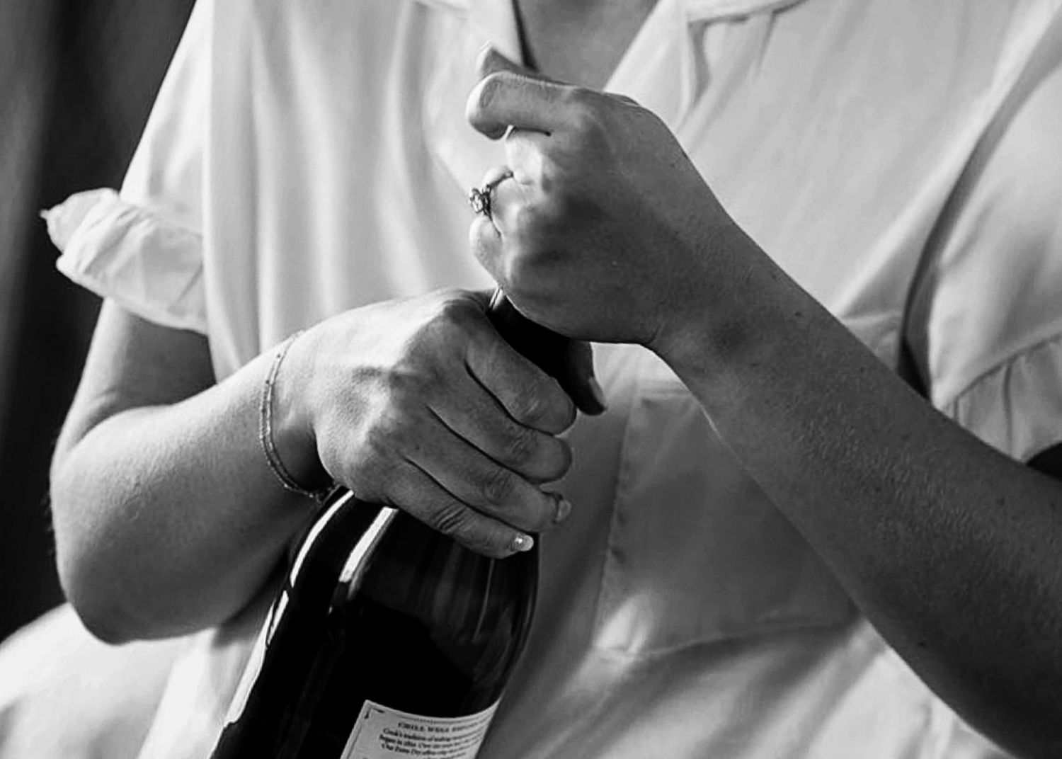 A group of people in white shirts stand together while drinking and socializing at a gathering.