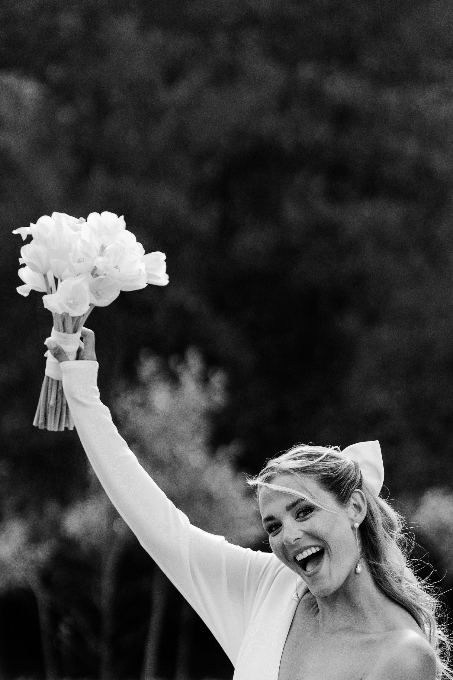 A black and white sequence of joyful celebratory moments with raised bouquets against a dark background.