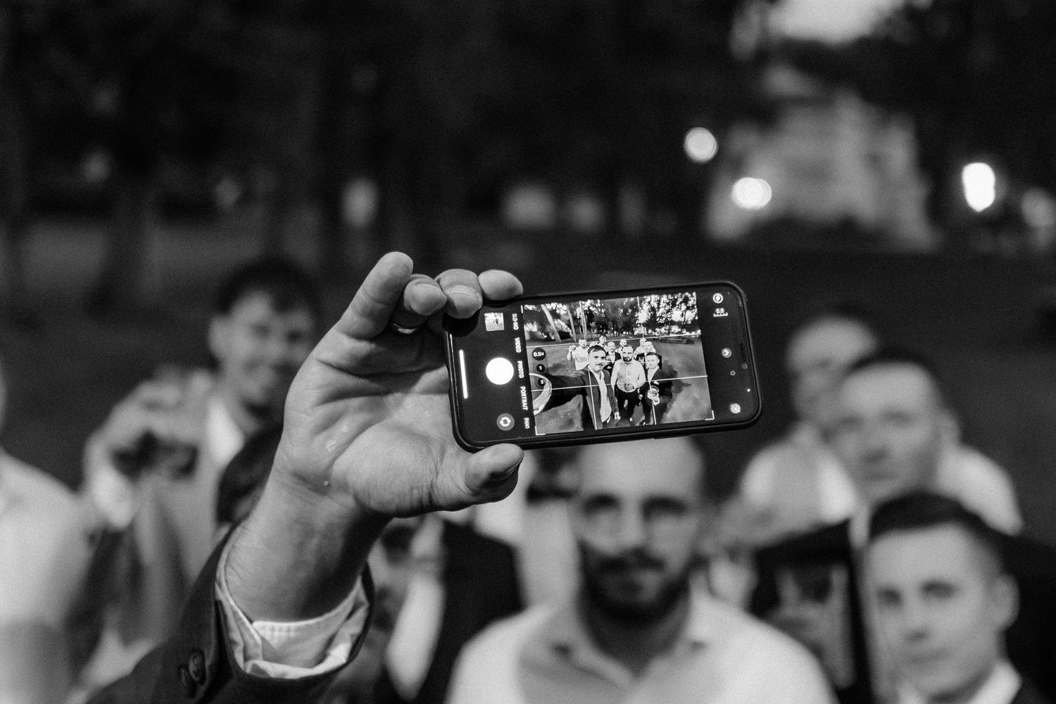 Guests taking photos with smartphones at an outdoor celebration.