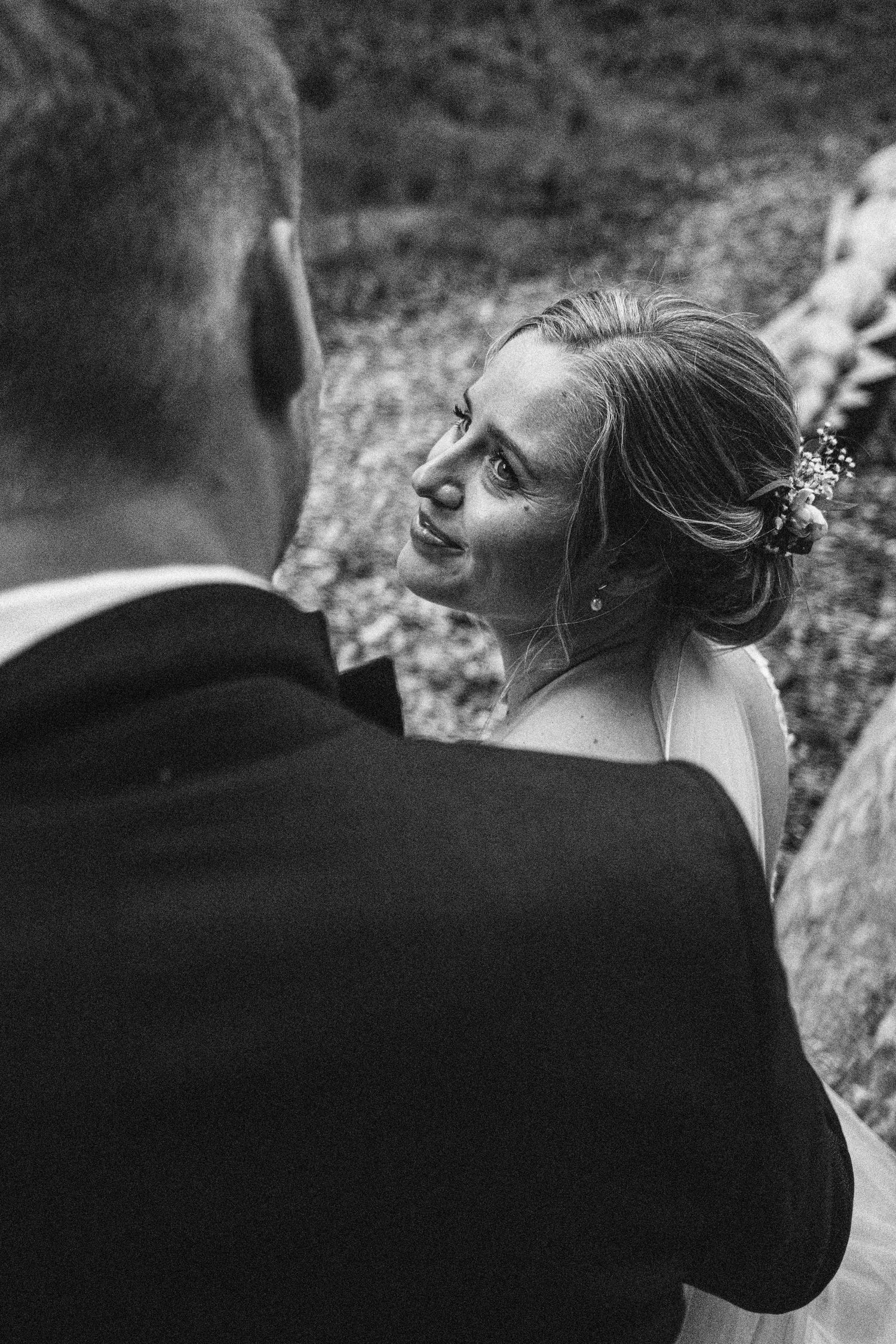 Black and white wedding photo series showing intimate moments between newlyweds from behind in an outdoor setting.