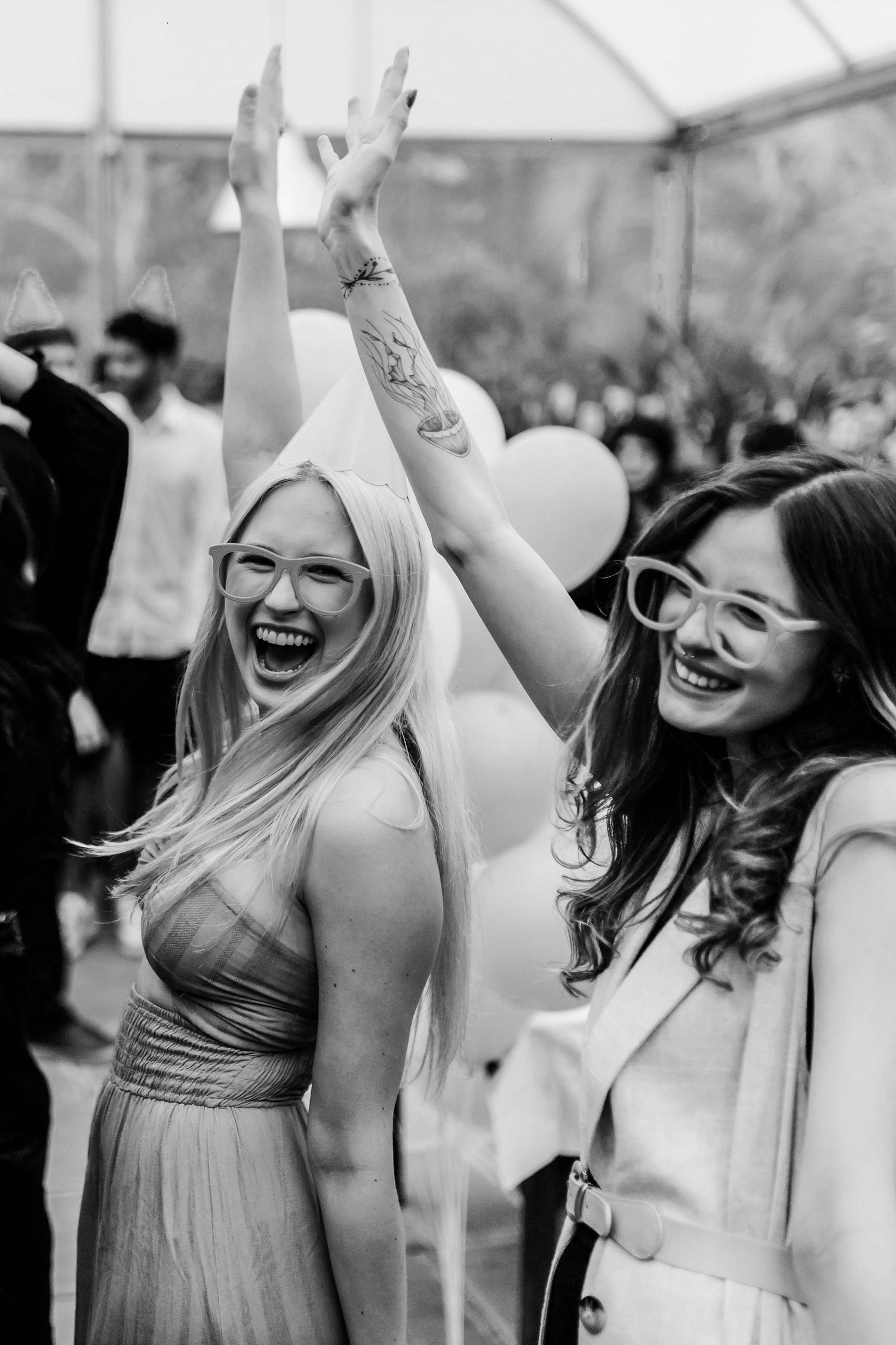 Black and white photo showing joyful people dancing and celebrating at what appears to be a wedding reception.