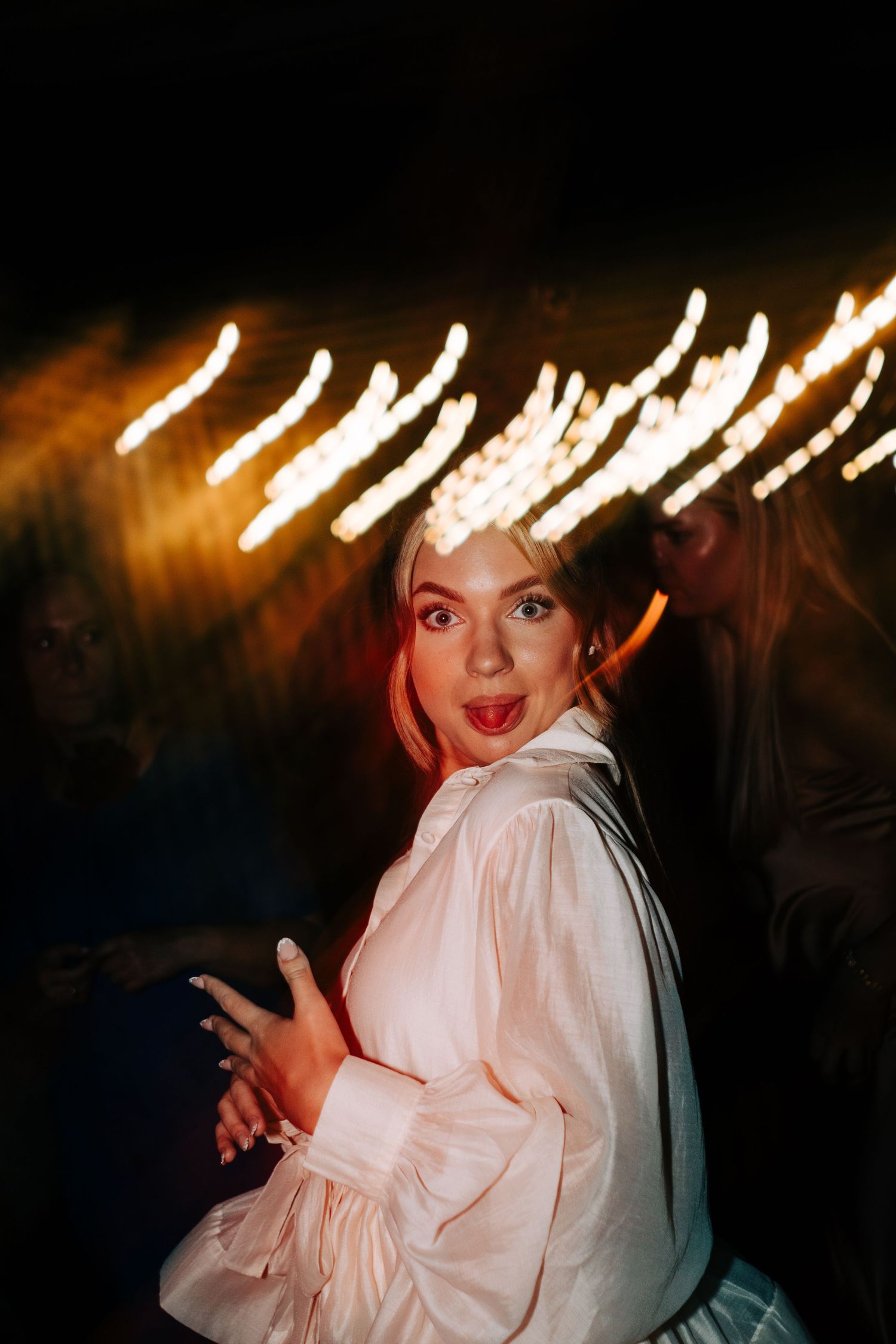A sequence of photos showing someone in a white blouse making expressive gestures against a dark background with light trails.