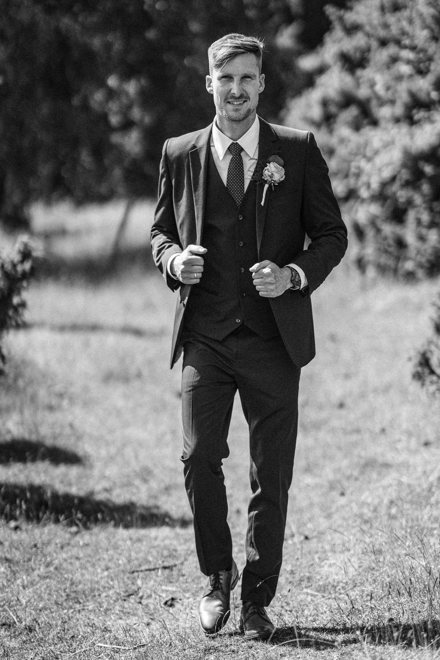 A series of black and white photos showing someone in a dark suit walking on a grassy path outdoors.