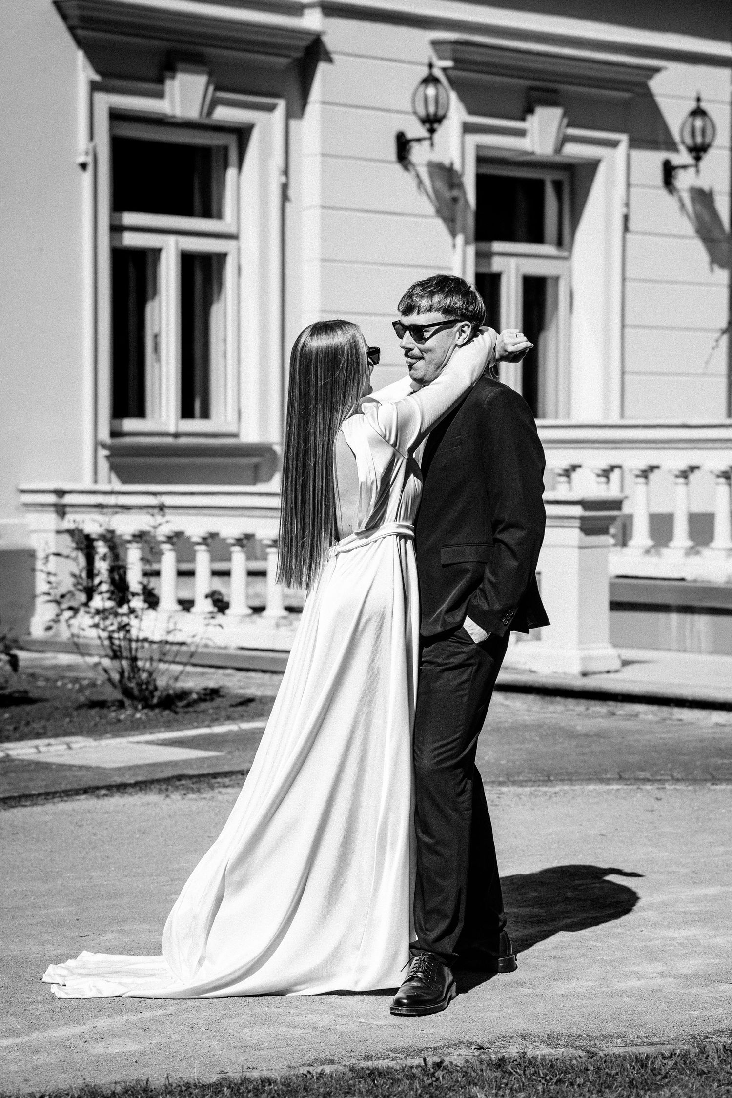 Classic black and white portrait of a couple in wedding attire against historic architecture.
