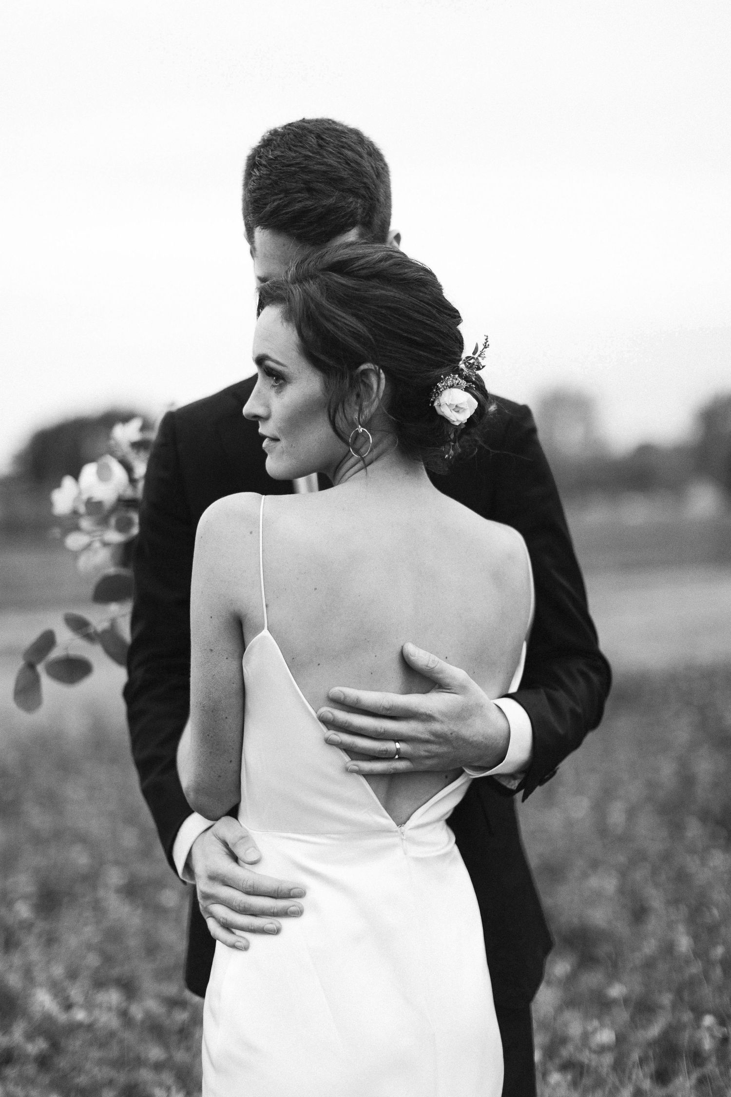 Black and white wedding photo series showing intimate moments between a couple embracing in a field.