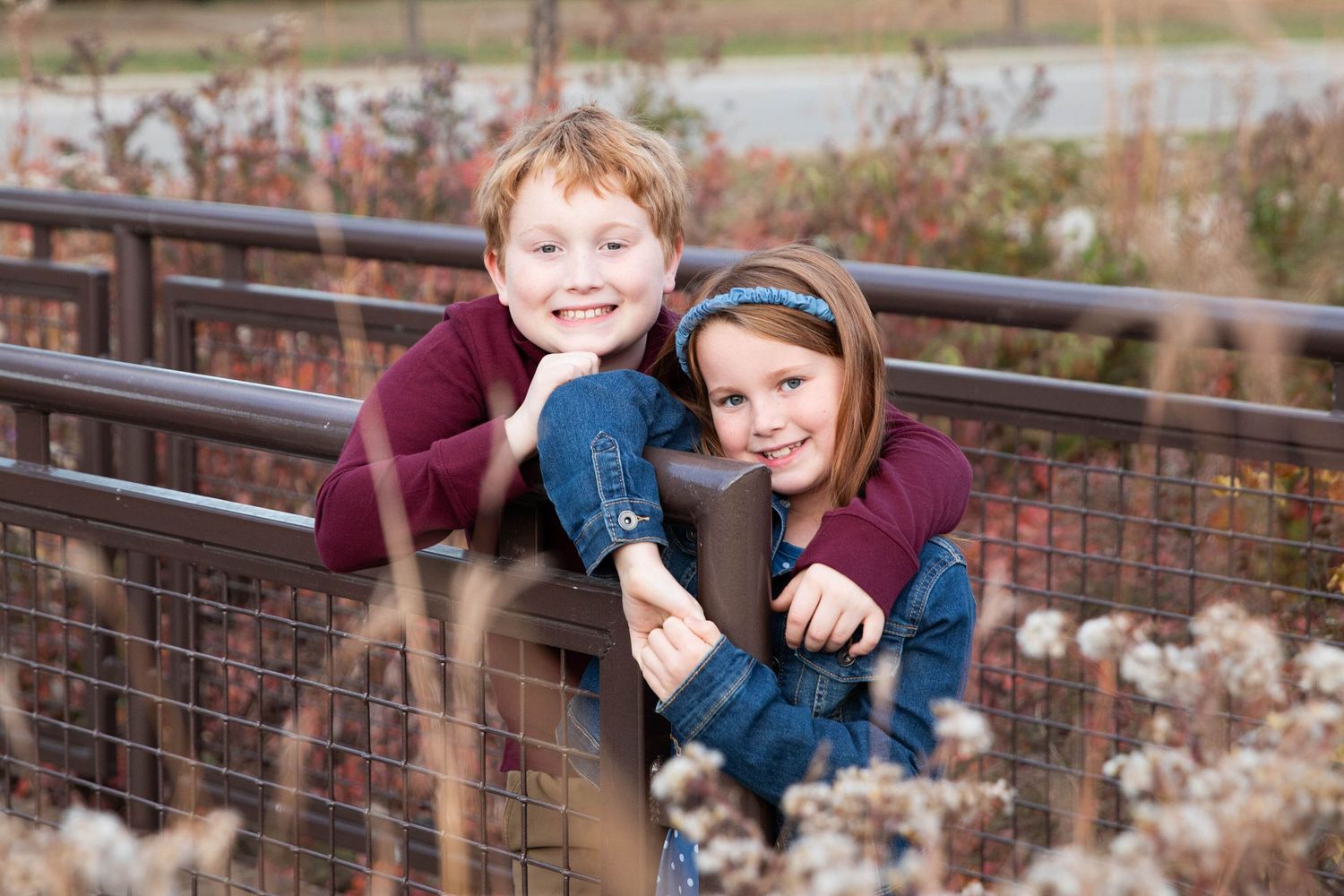 Family members playfully posing along outdoor railing in casual attire.
