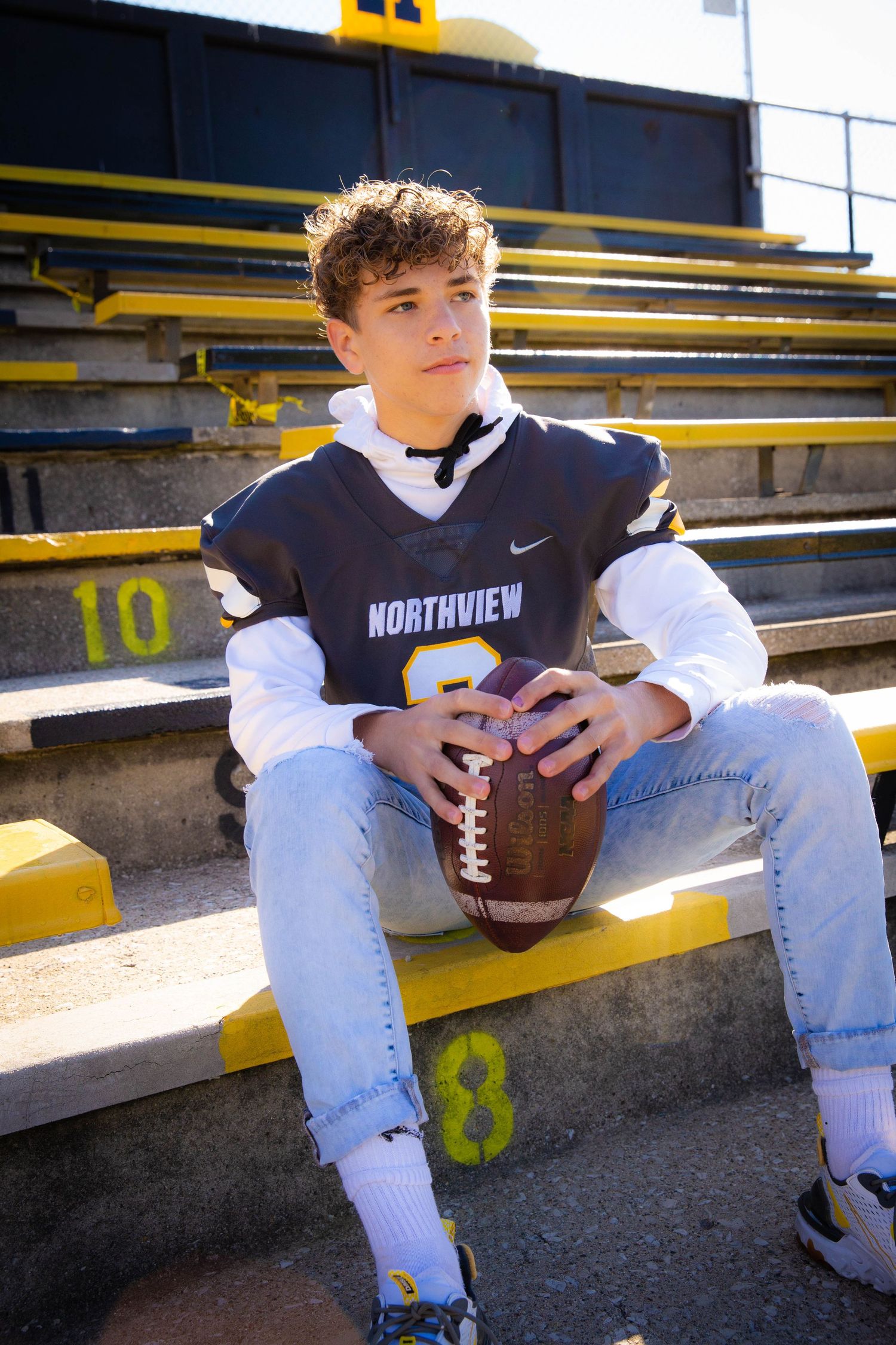 Football player in Northview jersey poses with ball on stadium bleachers.