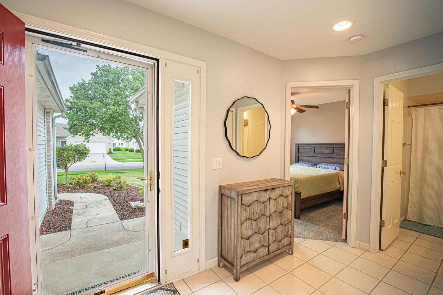 Bright hallway with tiled flooring and multiple doorways leading to different rooms.