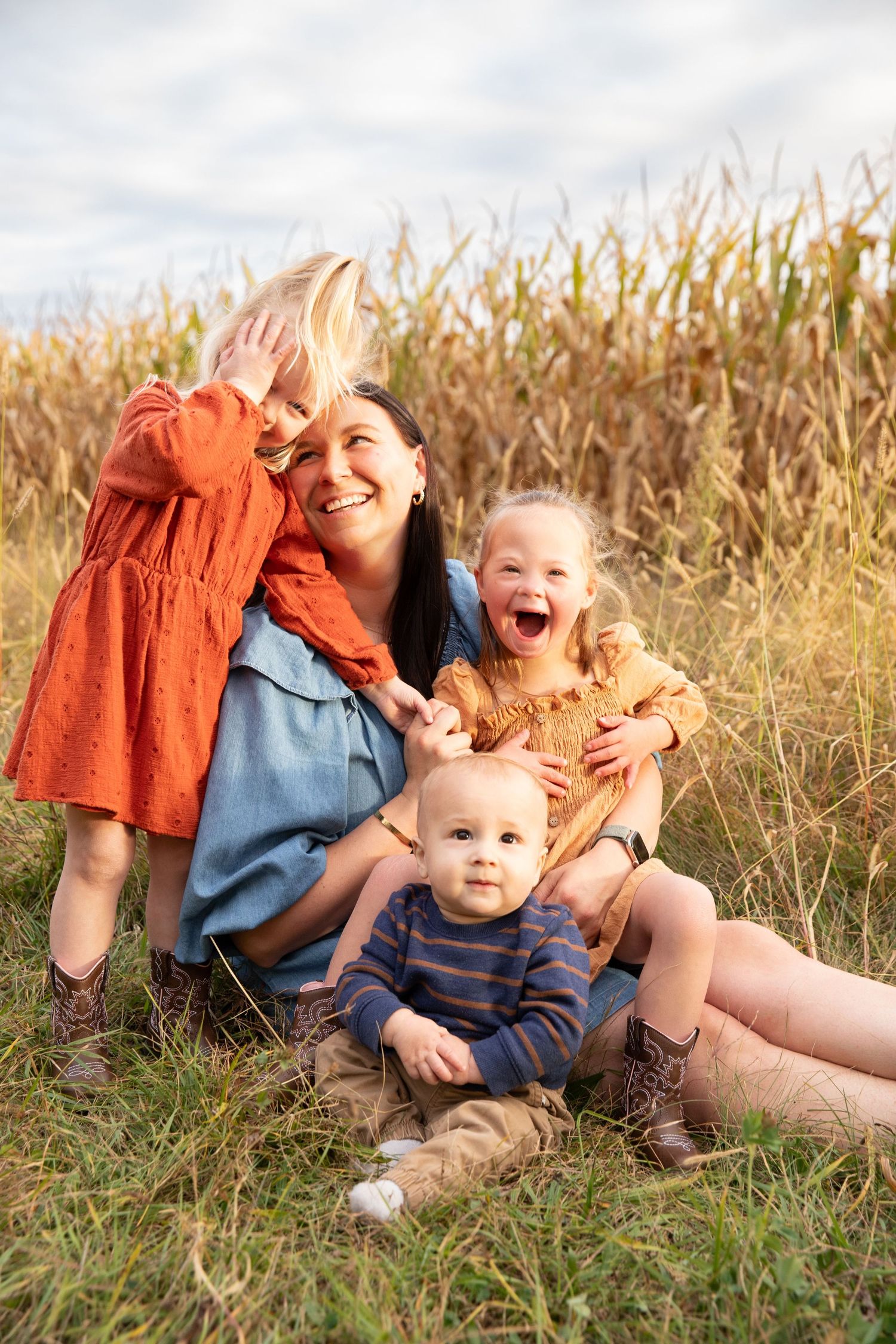 Playful family moment captured in a cornfield during golden hour with joyful expressions and casual attire.