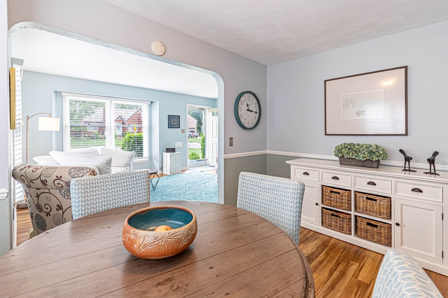 A panoramic view of a modern minimalist living room with hardwood floors and white walls showcasing natural lighting.
