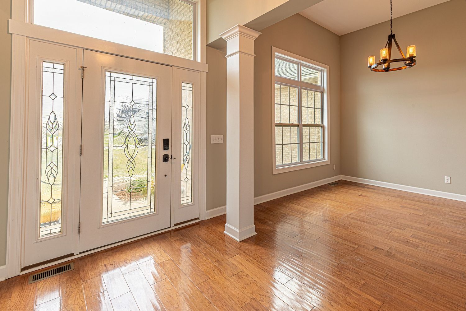 Bright and airy open concept living space with hardwood floors, white trim, and large windows letting in natural light.