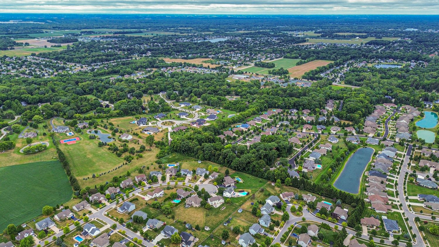 Aerial panoramic view of a residential neighborhood with green spaces and waterways.