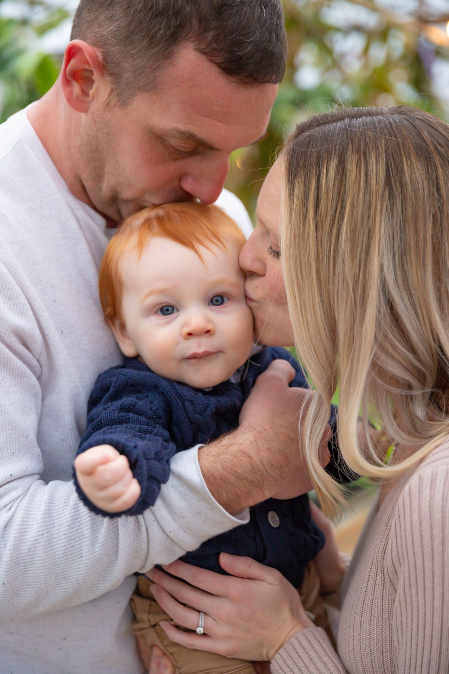 Intimate family portrait showing tender moments between parents and baby.