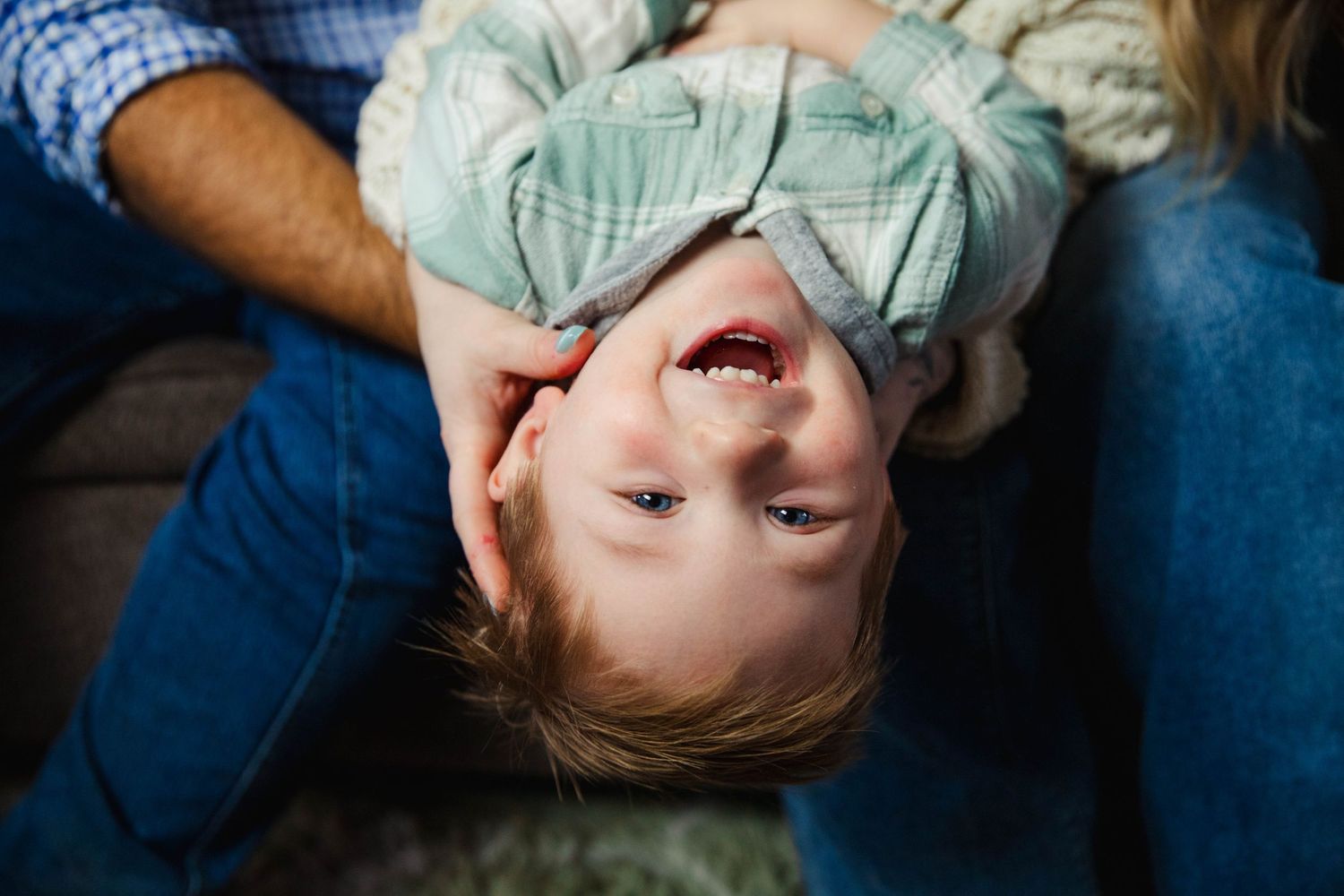 Couple shares tender moment while relaxing on blue couch during lifestyle photoshoot.