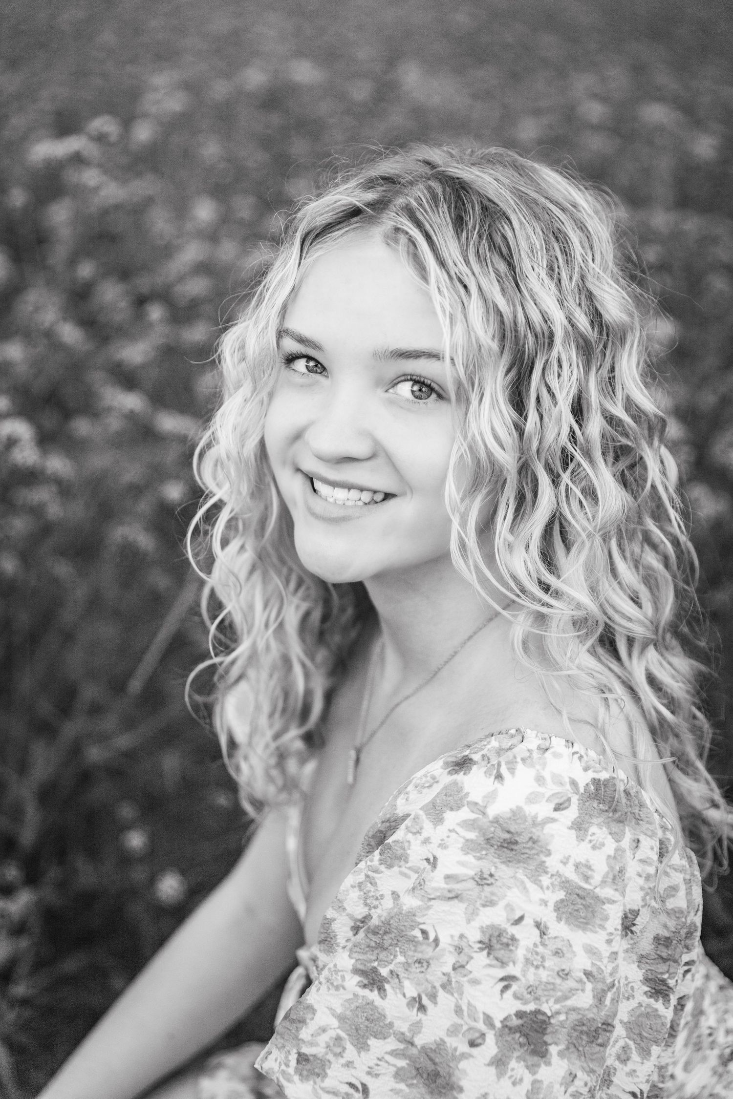 Outdoor portrait series featuring curly blonde hair and floral dress in natural setting.