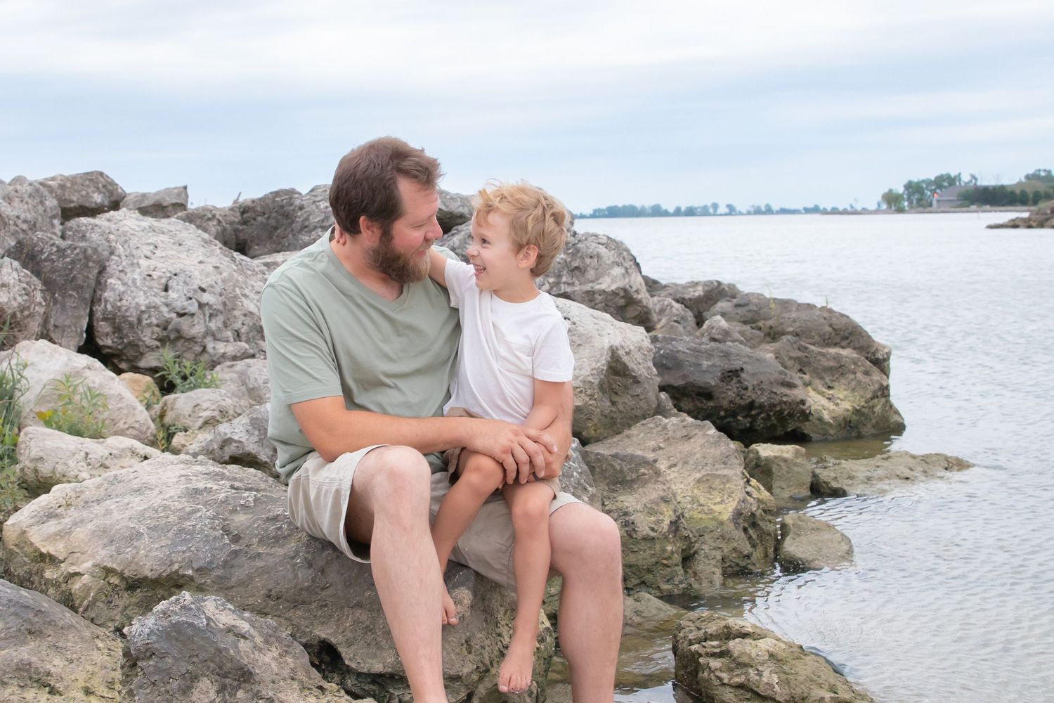 Couple enjoying intimate moments on rocky shoreline with water view.