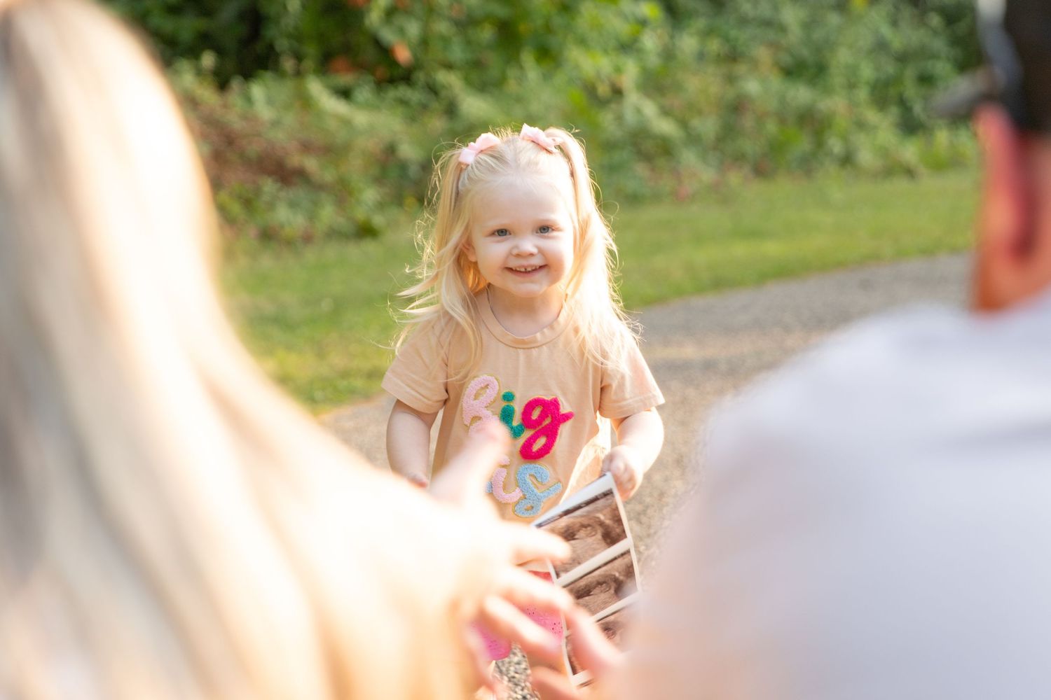 Young child playing outdoors in a grassy field on a sunny day.