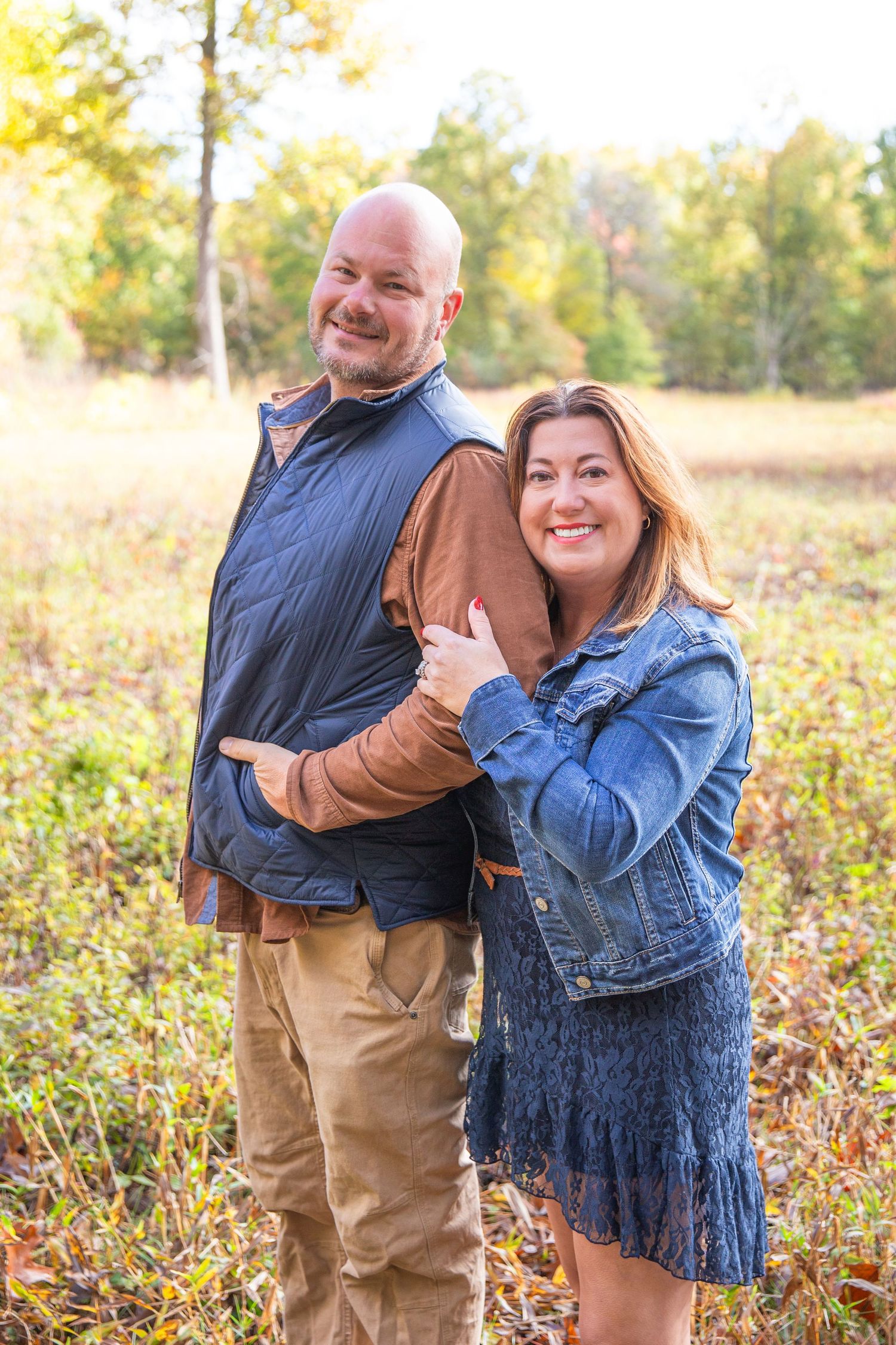 Casual outdoor couple photoshoot in autumn field with denim and khaki outfits.