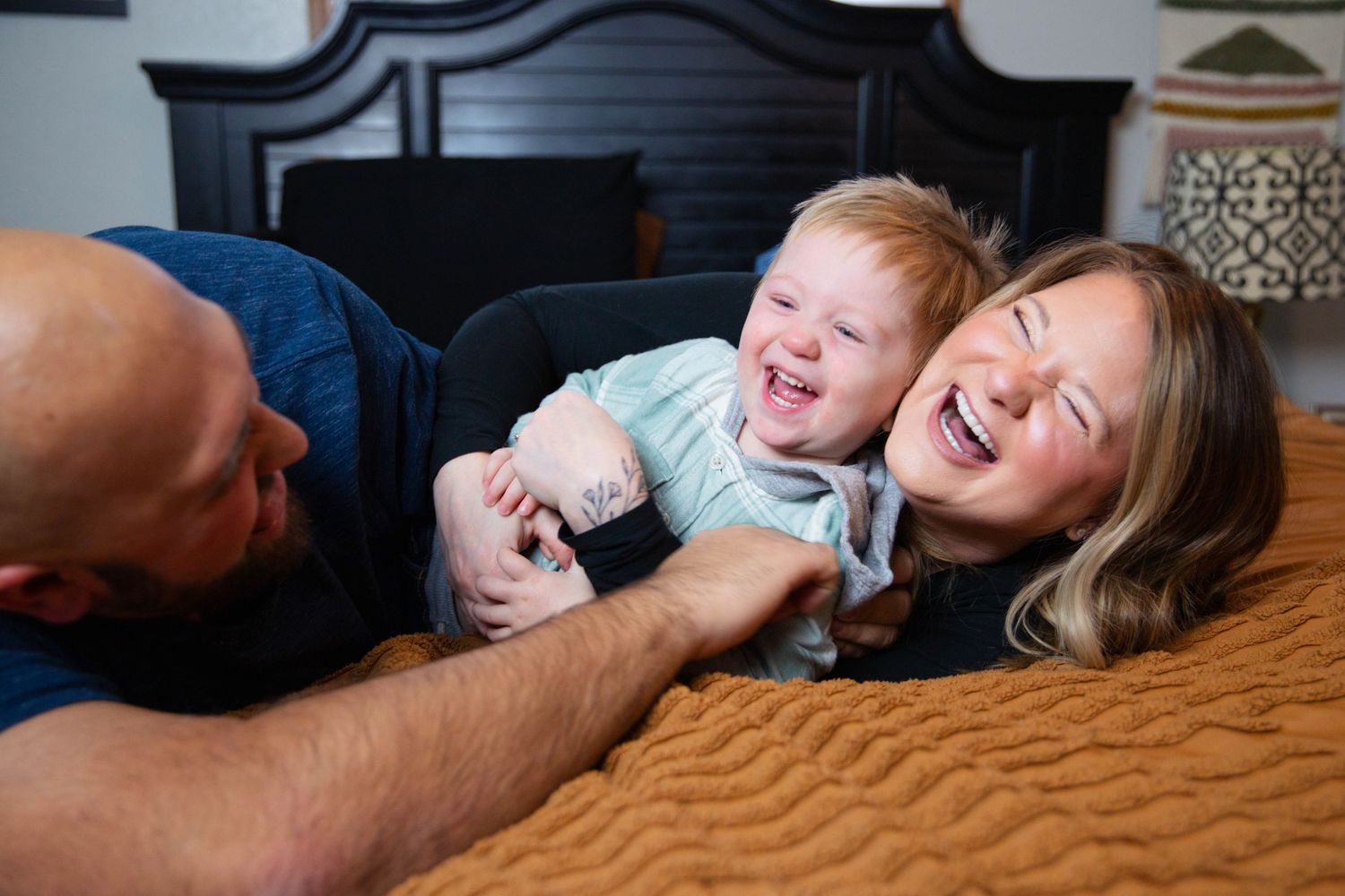 Playful family moments captured on a bed with natural lighting and joyful expressions.