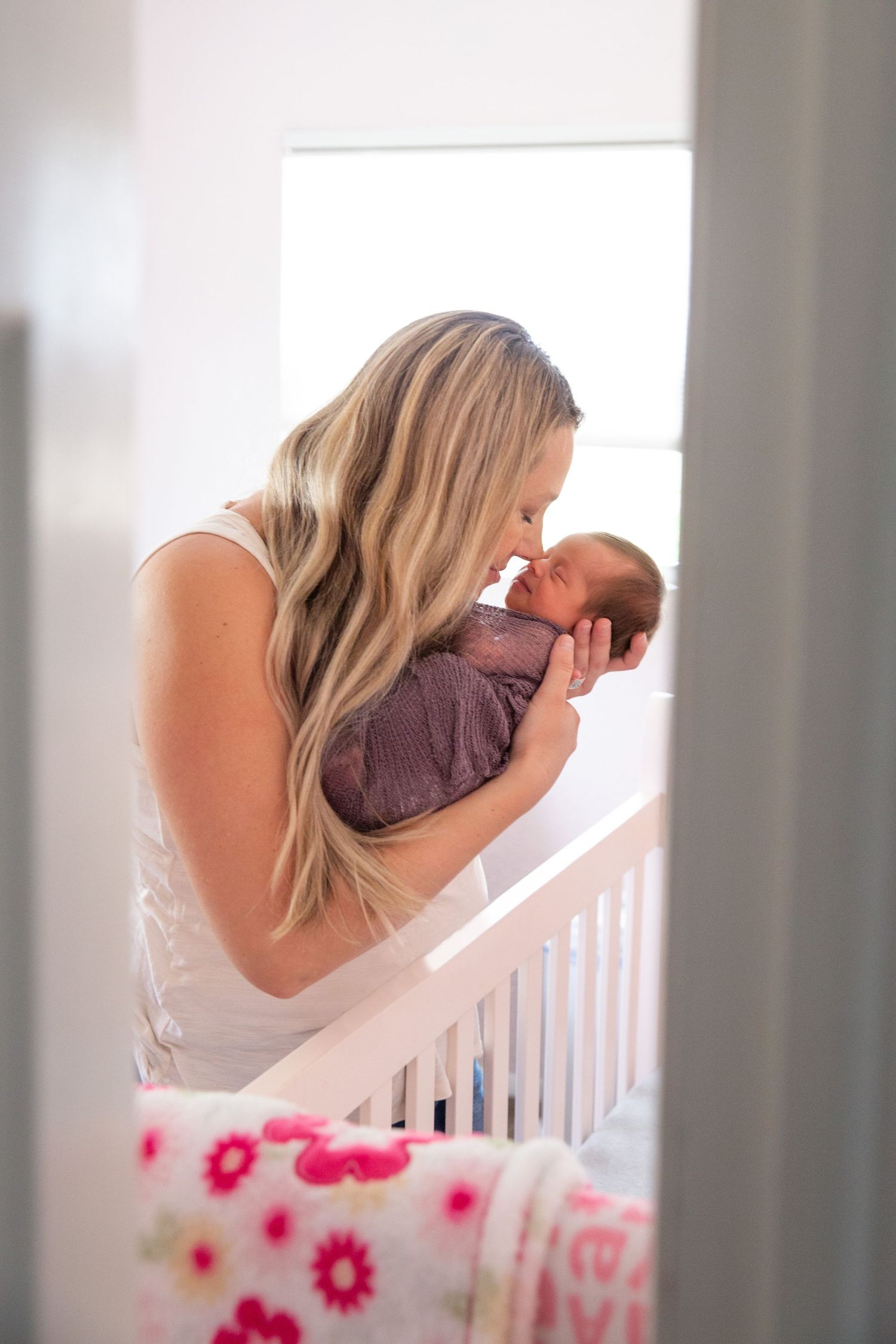 Tender moment between parent and baby in sunlit nursery.