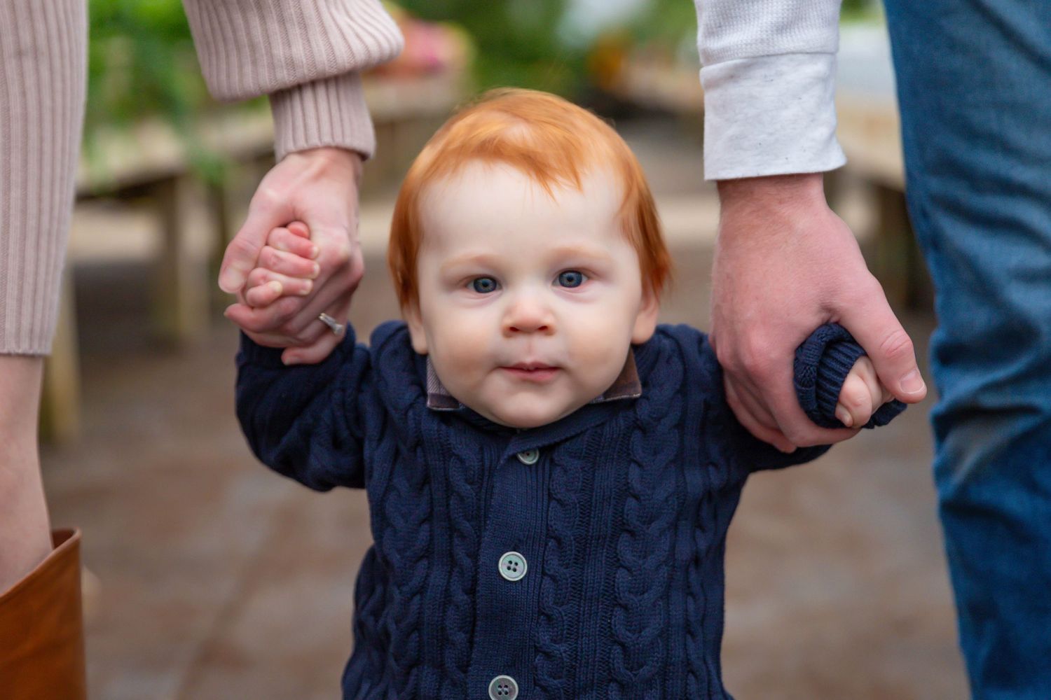 Series of photos showing a toddler in a navy sweater and jeans walking with support outdoors.