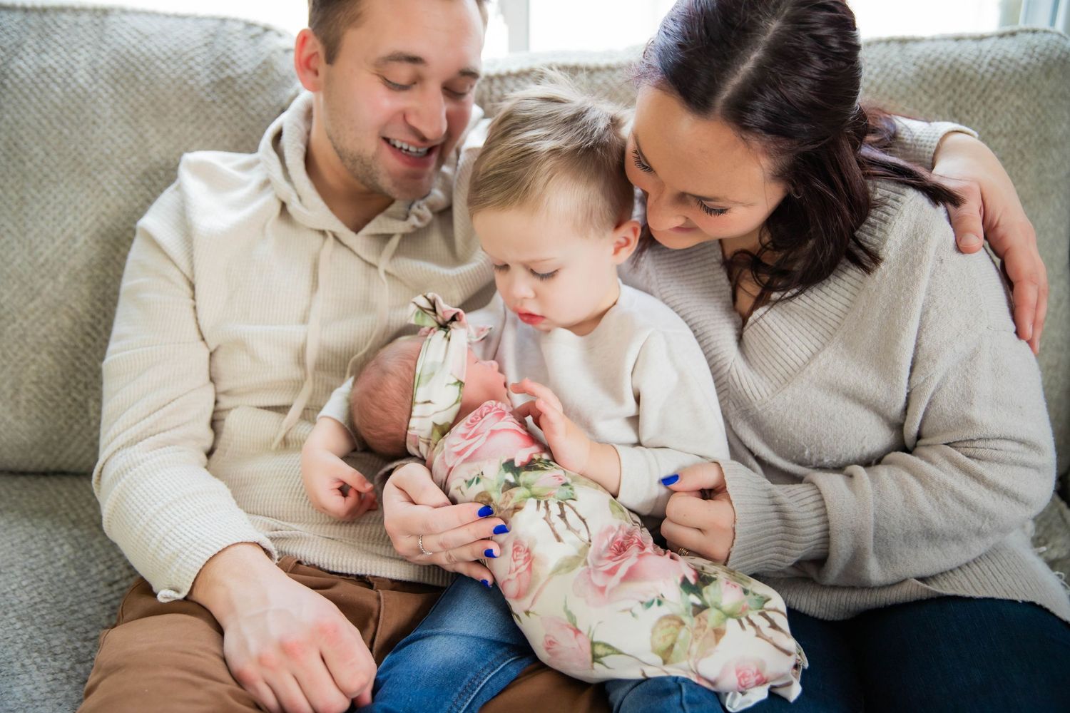 Family sharing tender moments while relaxing together on couch in casual attire.