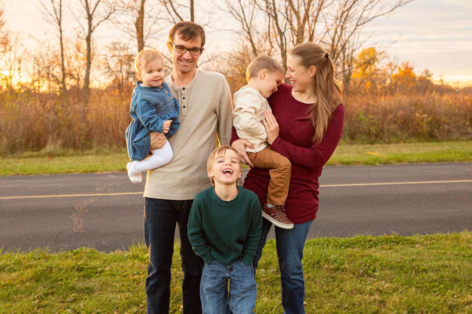 A group enjoys a playful moment together in a field at sunset with warm golden light in the background.