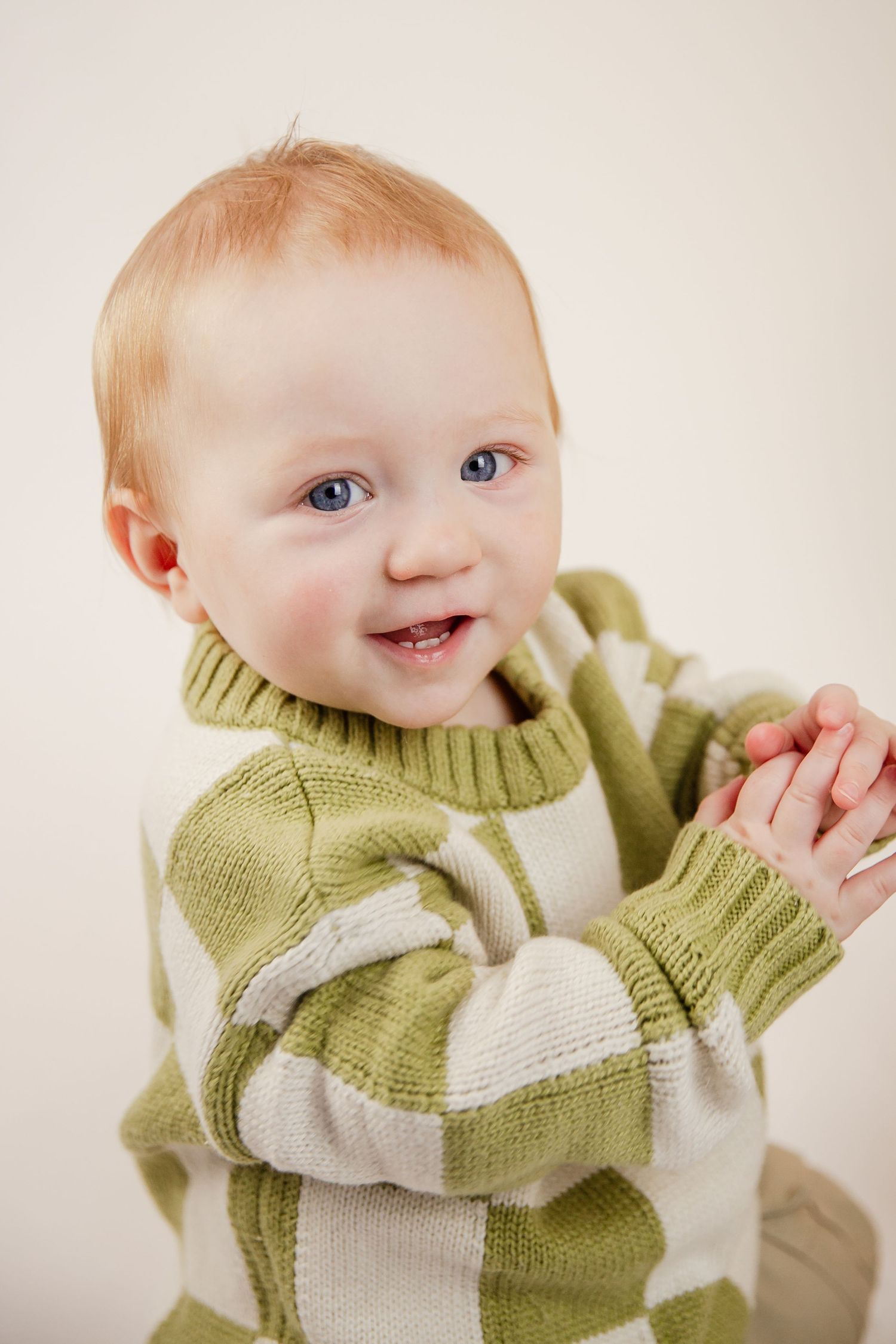 Baby wearing green and white knit sweater showing various happy expressions.