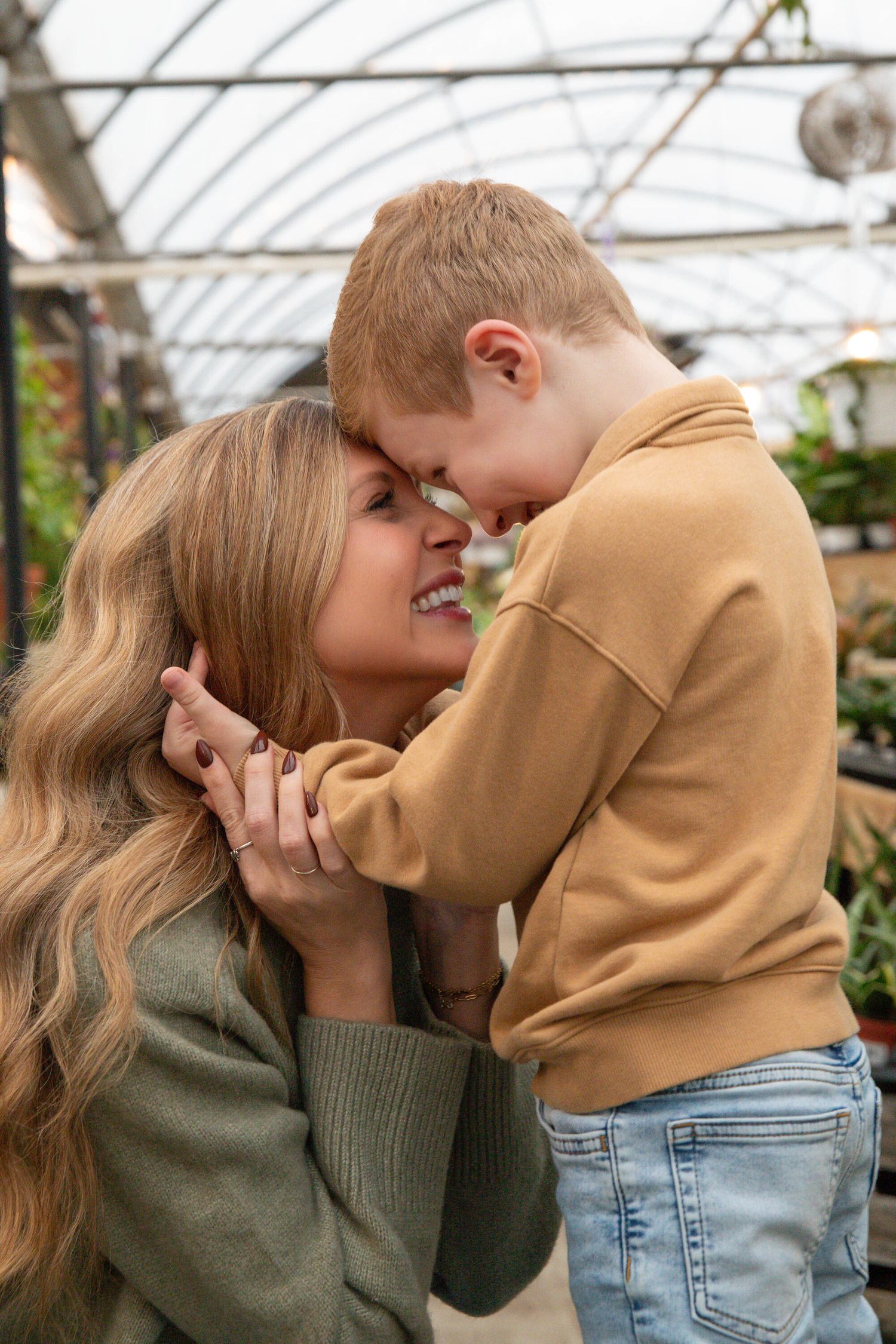 Mother and child sharing sweet moments in greenhouse with natural lighting.