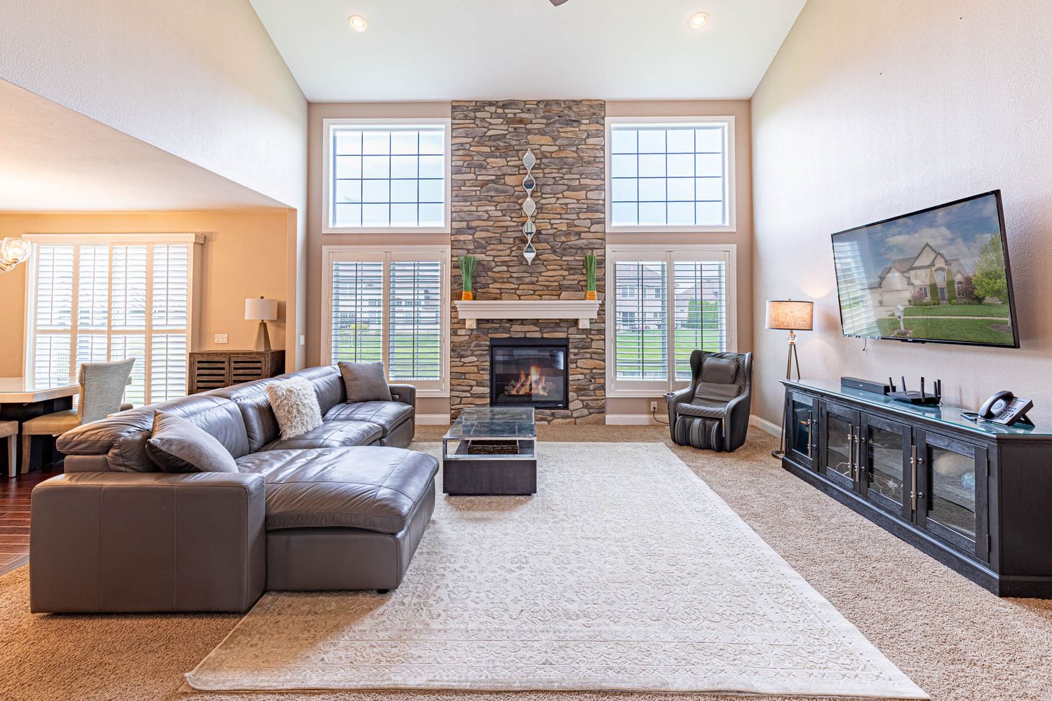 Family room featuring stone fireplace, large windows, and comfortable seating area.