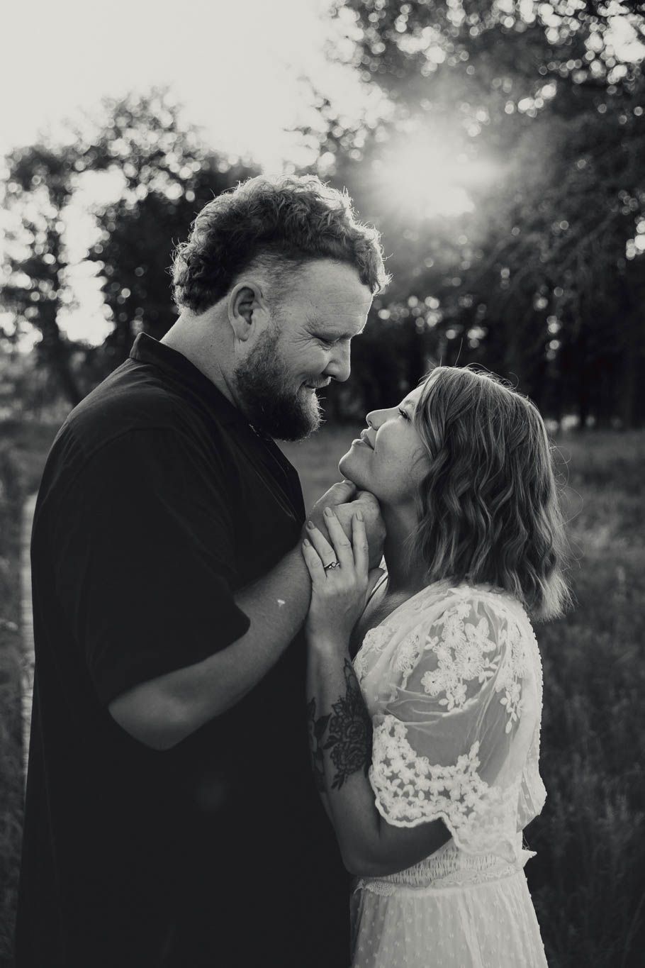 Romantic couple sharing intimate kisses in a sunlit outdoor setting with dreamy bokeh background.