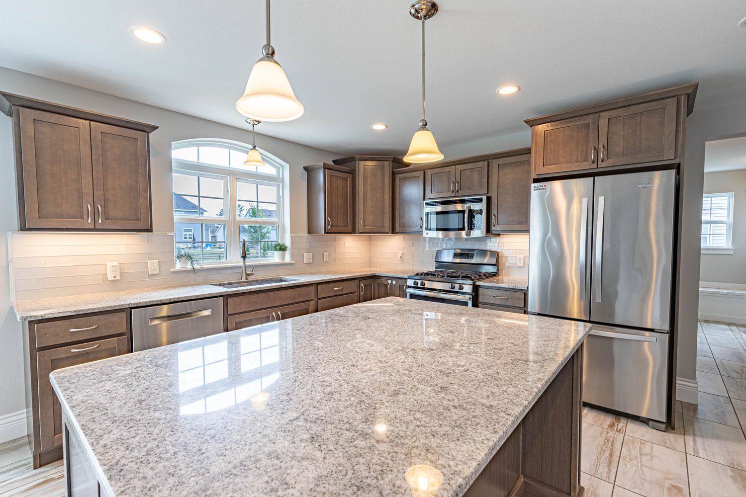Modern kitchen with granite countertops, stainless steel appliances, and pendant lighting.
