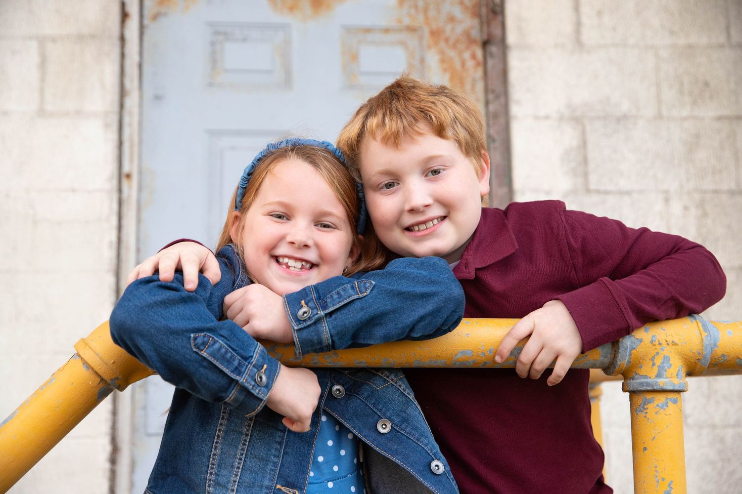 Children playing and laughing together against white brick wall background.
