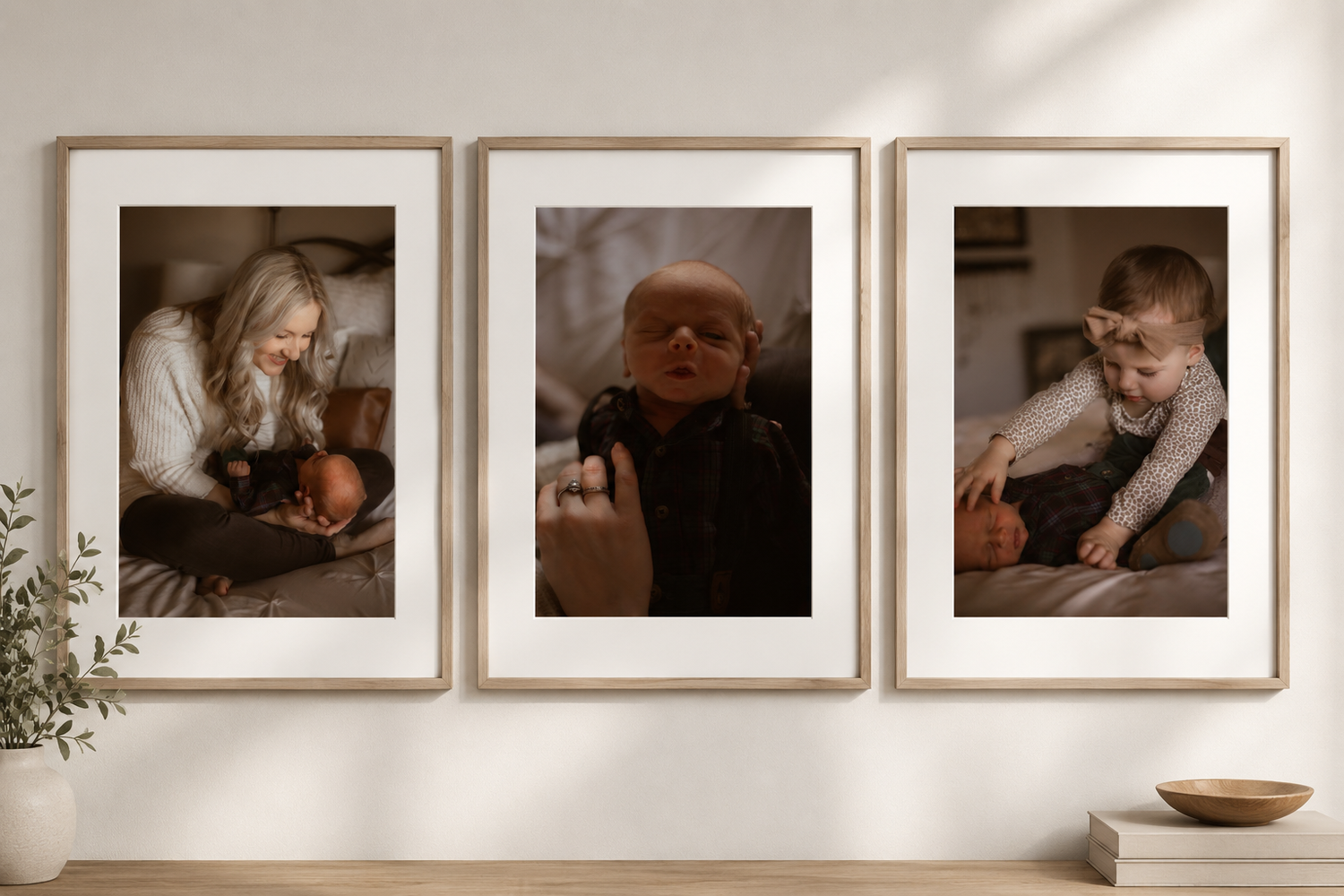 Three framed family photos on a wall featuring a mother with newborn, a baby portrait, and a child with parent.