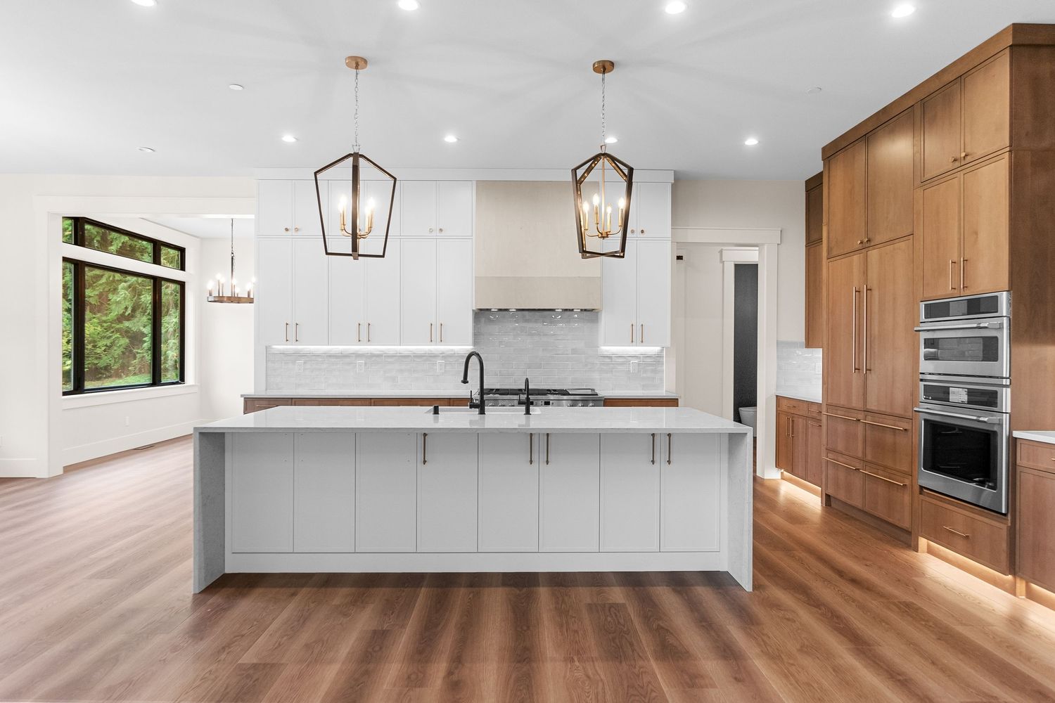 Contemporary white kitchen featuring warm wood cabinets and modern appliances.