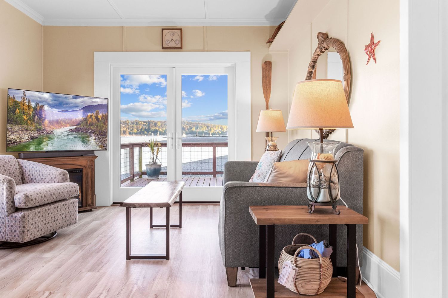 Coastal-themed living room with nautical decor featuring large windows offering stunning water views.
