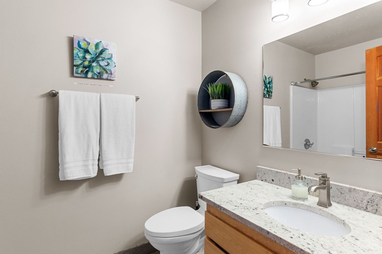Clean modern bathroom with white fixtures, granite countertop and decorative accents.