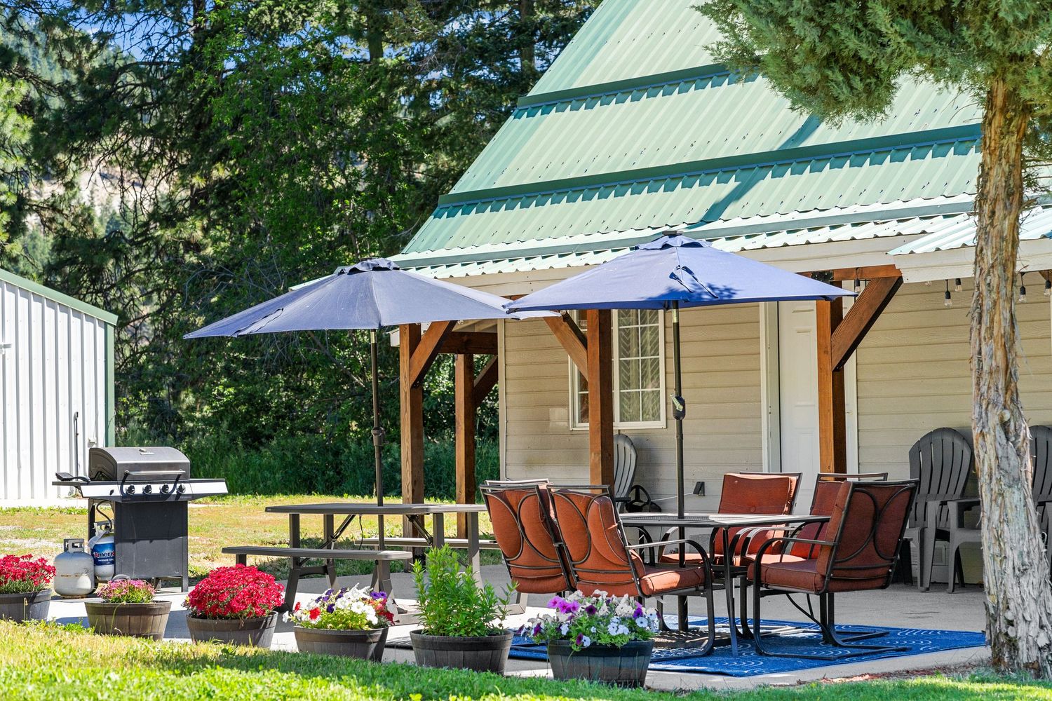 Exterior view of white cabins with green metal roofs and red outdoor seating arrangements.