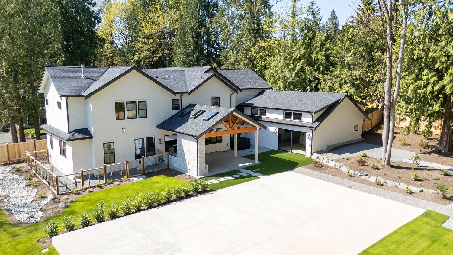 Modern farmhouse style home exterior with white siding and black trim surrounded by evergreen trees.