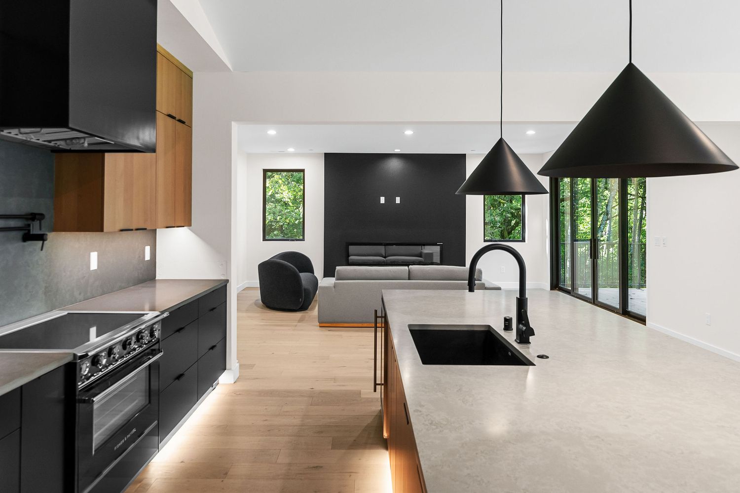 Modern living space with black accents and large windows overlooking green forest views.