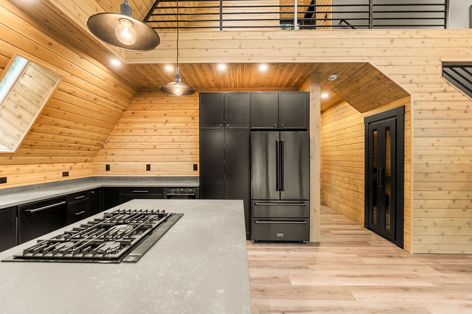 Contemporary kitchen with black appliances, grey countertops and wooden ceiling design.