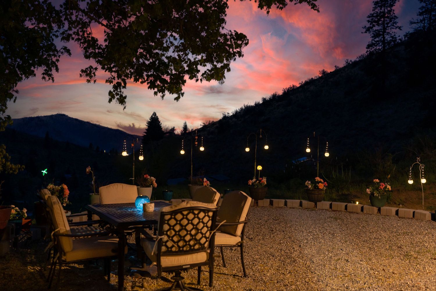 Stunning sunset view over mountains with outdoor seating area and string lights.