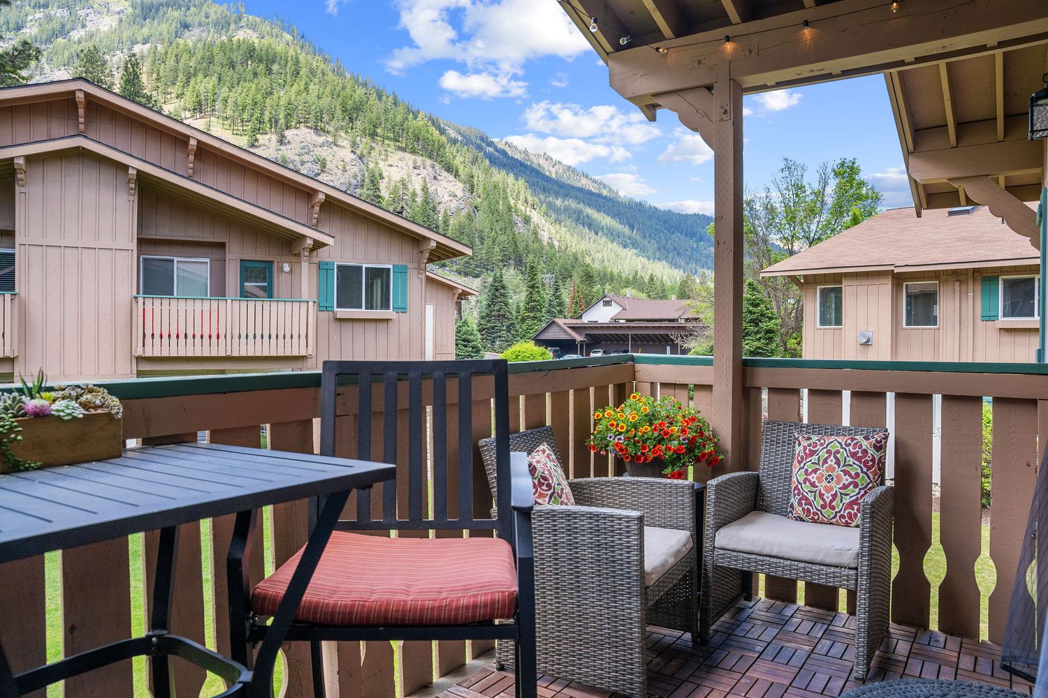 Mountain landscape view from condominium balcony with outdoor seating area.