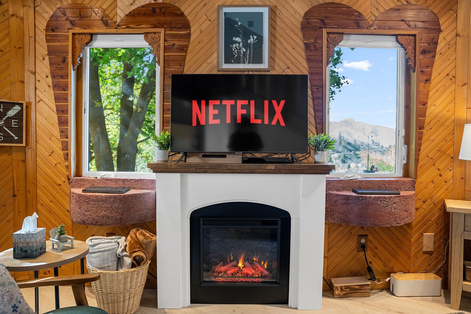 Cozy cabin interior with wood paneling featuring a fireplace, TV, and comfortable seating areas.
