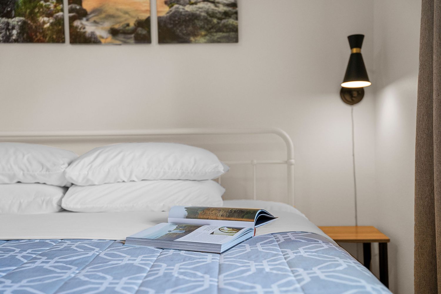 Clean bedroom with white bedding and wood accents against neutral walls.