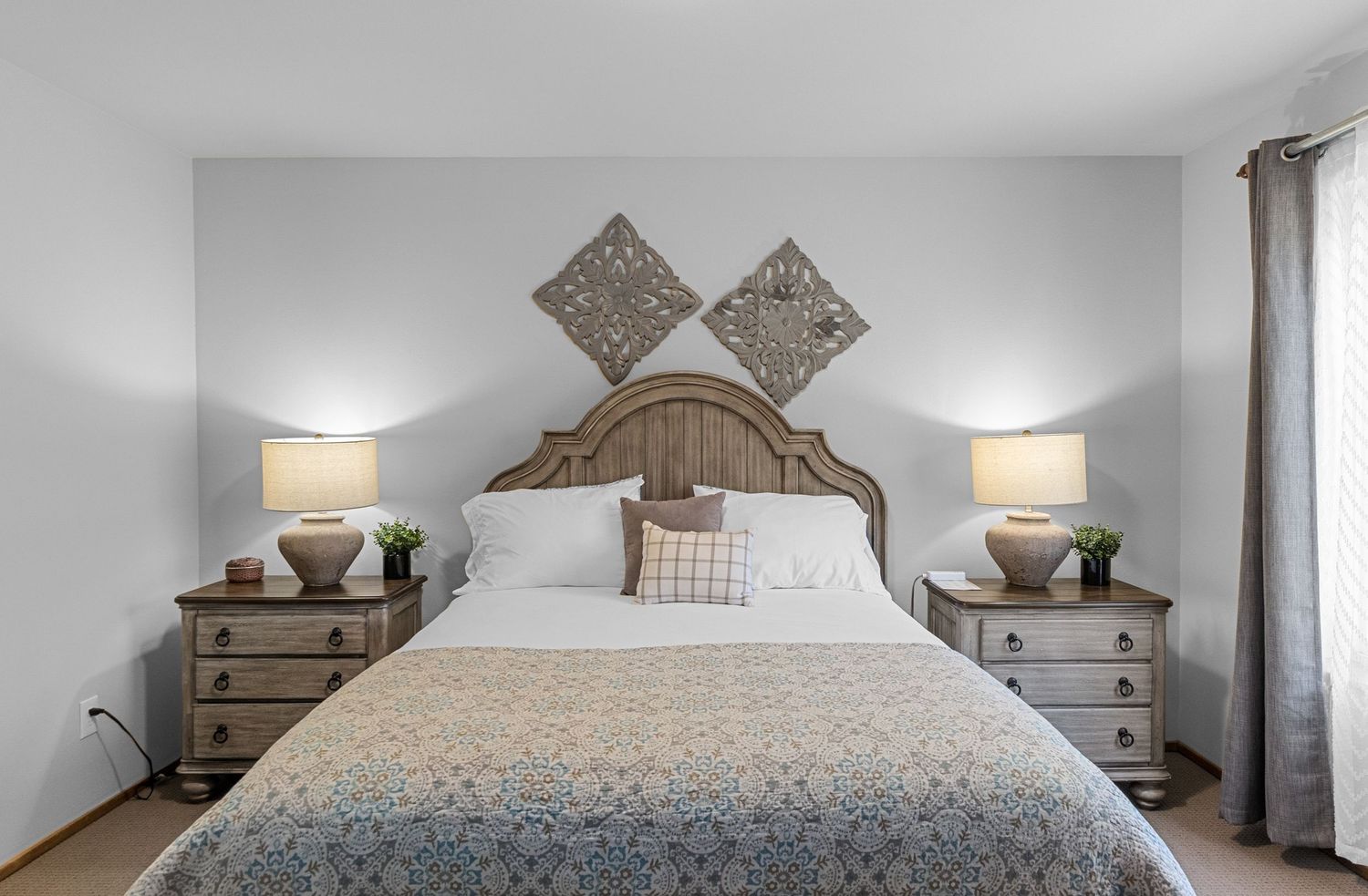Wide panoramic view of a tastefully decorated bedroom with neutral tones and wooden accents.