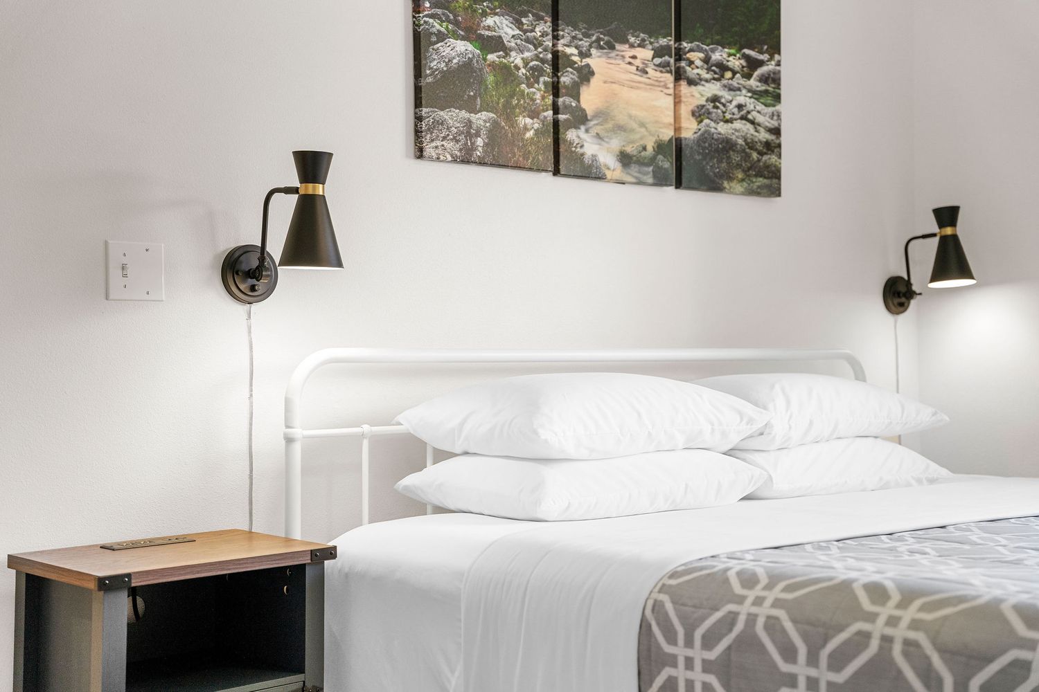 Contemporary bedroom design with grey and white color scheme and modern wall sconces.