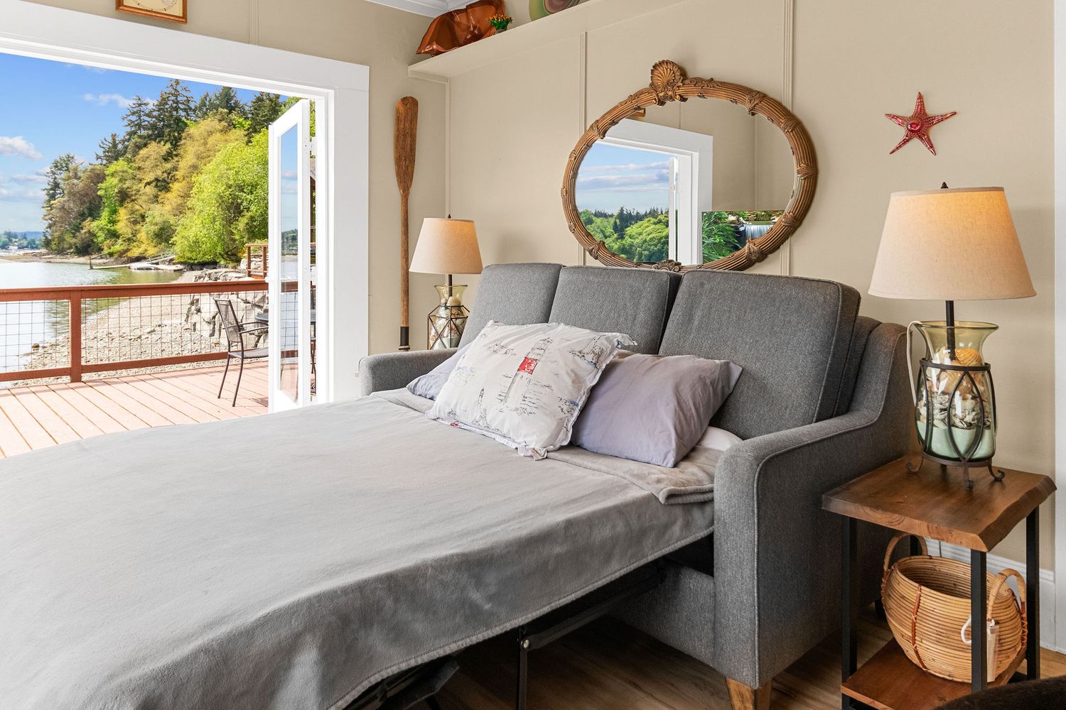 Modern bedroom with gray furnishings, white bedding, and large windows overlooking a scenic view.